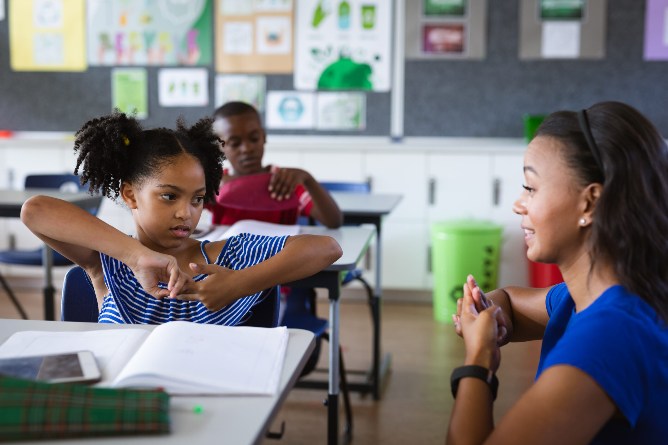 A teacher signing to her student. 